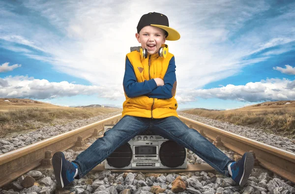 Chłopiec w Hip-Hopie siedzi na linii kolejowej i słuchanie vintage magnetofon. — Zdjęcie stockowe