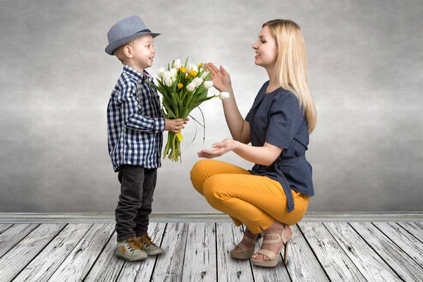 Unge son ger sin älskade mor en bukett vackra tulpaner. Våren, begreppet familjesemester. Kvinnodagen. — Stockfoto