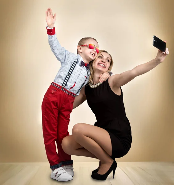Ung mor och son är fotograferade på en mobiltelefon, att göra selfie. Snygga, trendiga, moderna — Stockfoto