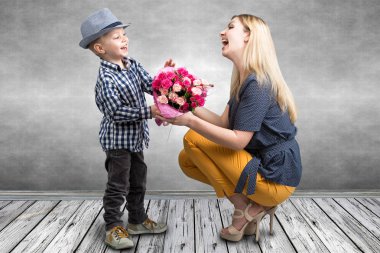 Küçük oğlu sevgili annesi pembe güller güzel bir buket verir. Bahar, kavram aile tatili. Kadınlar Günü, anneler günü.