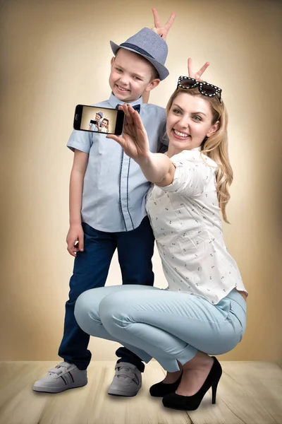 Ung mor och son är fotograferade på en mobiltelefon, att göra selfie. Snygga, trendiga, moderna — Stockfoto