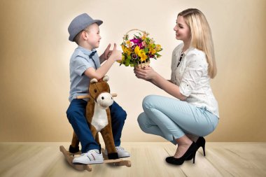 Oğlu ata, bir sepet çiçek sevgili anne verir. Küçük Prens sırtında. Bahar, kadınlar günü