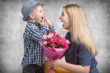 Küçük oğlu sevgili annesi pembe güller güzel bir buket verir. Bahar, kavram aile tatili. Kadınlar Günü, anneler günü.