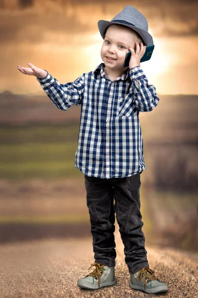 Un niño pequeño en un sombrero habla por su teléfono móvil.  . — Foto de Stock