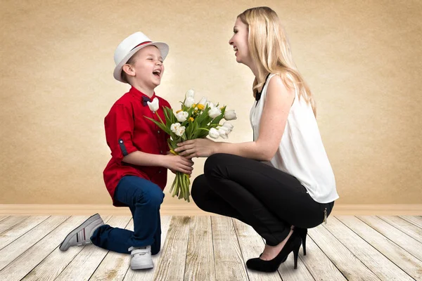 Eleganta son ger sin älskade mor en bukett vackra tulpaner. Våren, begreppet familjesemester. Kvinnodagen. — Stockfoto
