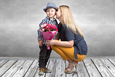 Küçük oğlu sevgili annesi pembe güller güzel bir buket verir. Bahar, kavram aile tatili. Kadınlar Günü, anneler günü.