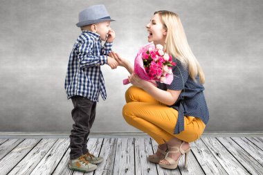 Küçük oğlu sevgili annesi pembe güller güzel bir buket verir. Bahar, kavram aile tatili. Kadınlar Günü, anneler günü.