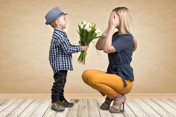 Liten son ger sin älskade mor en bukett vackra tulpaner. Våren, begreppet familjesemester. Kvinnodagen. — Stockfoto