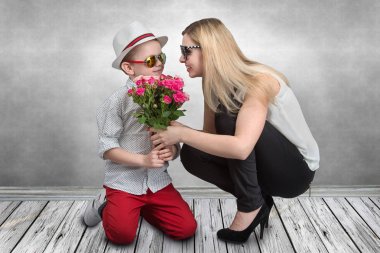 Küçük oğlu sevgili annesi pembe güller güzel bir buket verir. Bahar, kavram aile tatili. Kadınlar Günü, anneler günü.