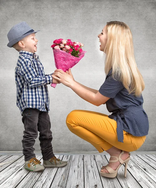 Liten son ger sin älskade mor en vacker bukett av rosa rosor. Våren, begreppet familjesemester. Kvinnodagen, mors dag. — Stockfoto