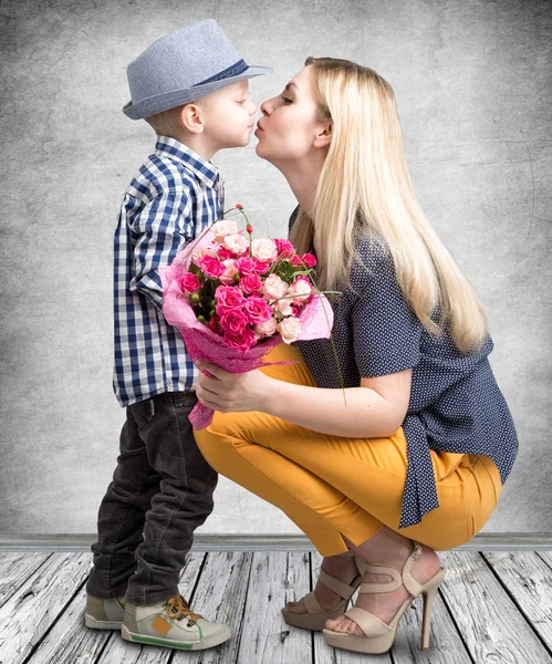 小儿子给他心爱的母亲一束美丽的粉红玫瑰，亲吻妈妈。春、 妇女节、 母亲节这一天. — 图库照片