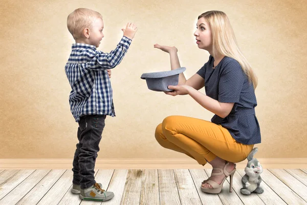 Tricks med en kanin. En ung mamma visar lilla pojken trollkonster kanin i hatten. Familjevänligt, underhållning. — Stockfoto