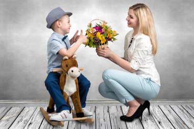 Oğlu ata, bir sepet çiçek sevgili anne verir. Küçük Prens sırtında. Bahar, kadınlar günü, anneler günü.