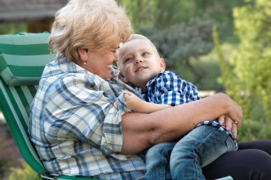 Kucağında oturan küçük torunu kucaklama büyük annesi. Aile tatili açık havada.