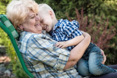 Sevgili büyükanne kolları üzerinde oturan çocuk. Öpüp nazik. Nesiller seviyorum.
