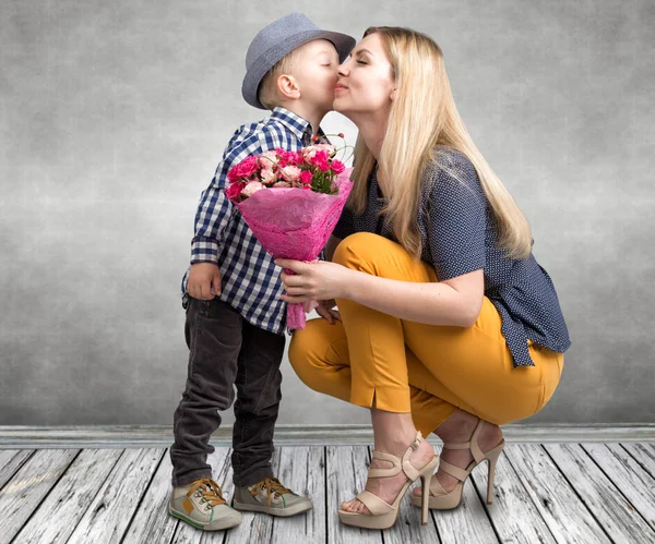 小儿子给他心爱的母亲一束美丽的玫瑰和亲吻妈妈的脸颊。春、 妇女节、 母亲节这一天. — 图库照片