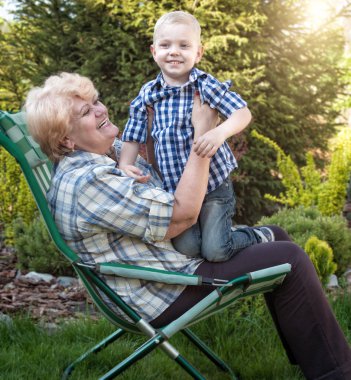 Kucağında oturan küçük torunu kucaklama büyük annesi. Aile tatili açık havada.