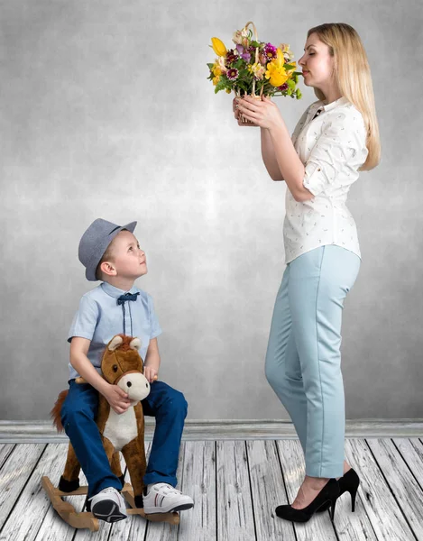 Sonen på hästen, ger en korg med blommor älskade mor. Lilla prinsen på hästryggen. Våren, kvinnodagen — Stockfoto