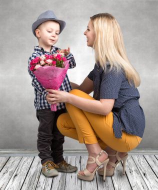 Küçük oğlu sevgili annesi pembe güller güzel bir buket verir. Bahar, kavram aile tatili. Kadınlar Günü, anneler günü.