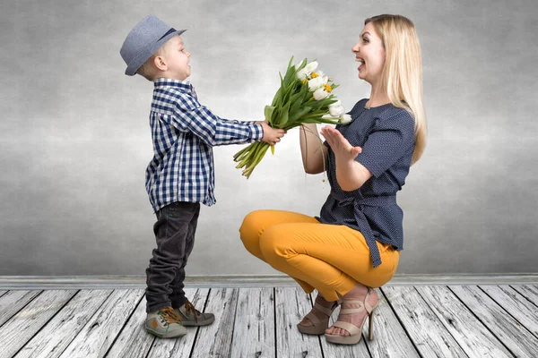 Liten son ger sin älskade mor en bukett vackra tulpaner. Våren, begreppet familjesemester. Kvinnodagen. — Stockfoto