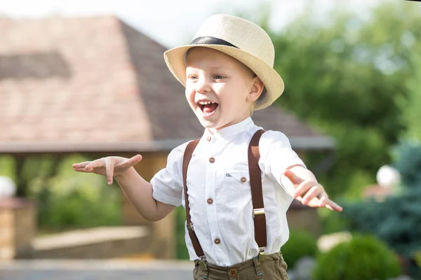 Un niño pequeño con sombrero de paja camina por el parque . — Foto de Stock