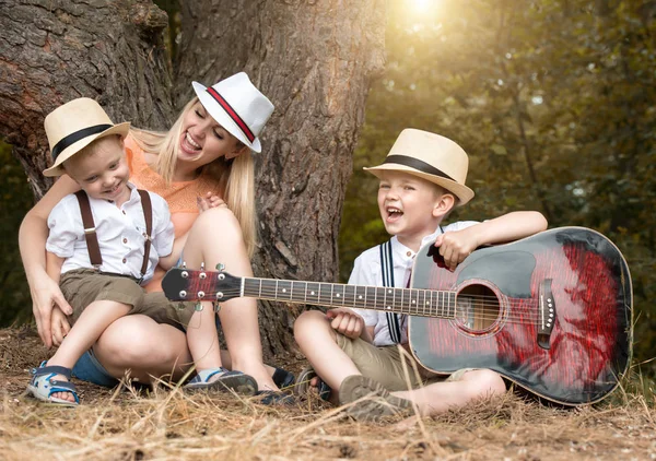 Genç anne ve iki oğlu ormanda, Zihnimin içinde şarkılar bir gitar ile dinlenme.