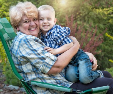 Sevgili büyükanne kolları üzerinde oturan çocuk. Öpüp nazik. Hafta sonu kır evi.