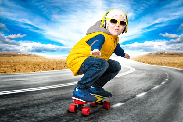 Niño haciendo trucos en un monopatín, patinar en la carretera.El niño pequeño en el estilo de Hip Hop  . — Foto de Stock