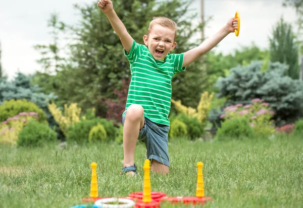 Lindo chico jugando un juego de lanzar anillos al aire libre en verano Park.The alegría de la victoria . — Foto de Stock