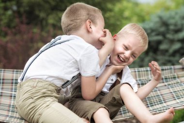 İki kardeş dinlen, sırları kulağına söylüyor. Çocuklar hamakta binmek.
