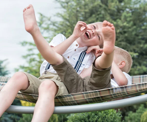Los dos hermanos están descansando y divirtiéndose. Los niños montan en una hamaca . — Foto de Stock