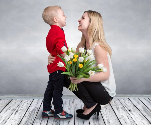 小儿子给他心爱的母亲一束美丽的郁金香。春天，概念的家庭度假。妇女节. — 图库照片
