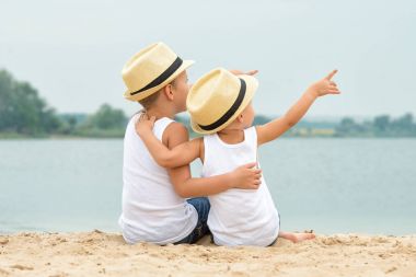 Hasır şapkalar göl kıyısında oturan iki kardeş. Ve gökyüzüne bak.
