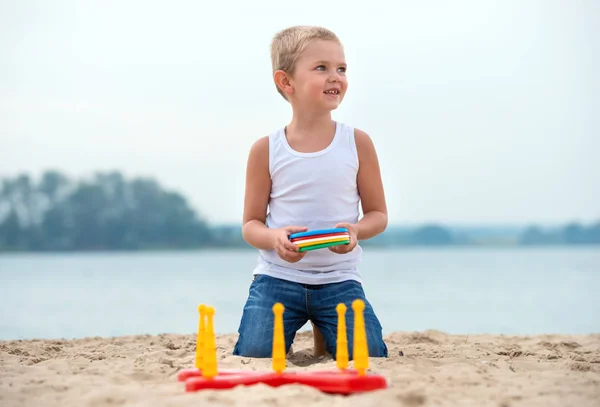 Cute boy playing a game throwing rings on the seafront.The joy of victory. — Stock Photo, Image