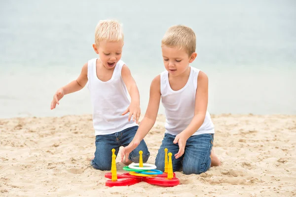 Dos hermanos están caminando y jugando en la playa.El juego es un lanzamiento de anillo . — Foto de Stock