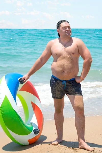 El hombre con el anillo de goma en la playa.Vacaciones de verano . —  Fotos de Stock