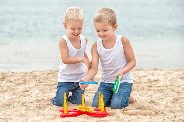 Dos hermanos están caminando y jugando en la playa.El juego es un lanzamiento de anillo . — Foto de Stock
