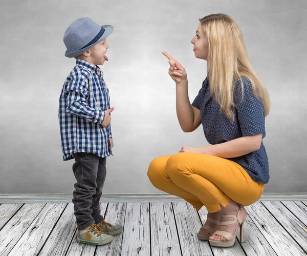 A young mother scolds her naughty little son.Boy showing tongue and teases mom. — Stock Photo, Image