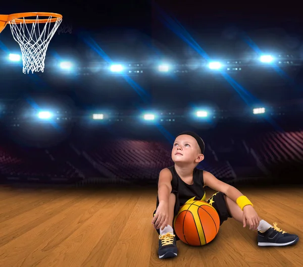 Garçon joueur de basket-ball avec une balle assise sur le sol dans la salle de gym et rêves de grandes victoires . — Photo