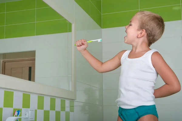 El niño canta la canción en el cepillo de dientes en el baño.El futuro cantante . — Foto de Stock