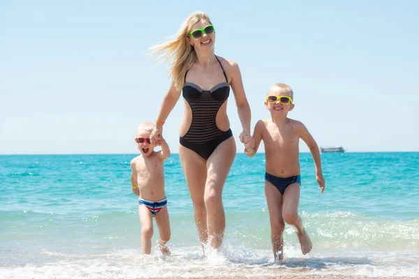 Güzel anne ve dalgalar üzerinde çalışan iki güzel oğlum tutuşup. Eğlenceli, Aile dostu yaz tatili. — Stok fotoğraf