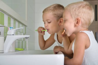 Two brothers brush my teeth in the bathroom.The beginning of a new day clipart