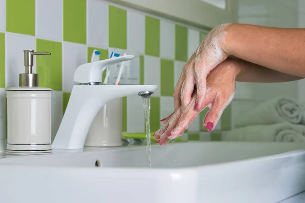 Женщина моет руки с мылом в ванной . — стоковое фото