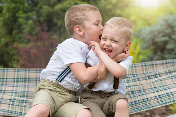 Dwóch braci odpoczynku, telling secrets w jego ucho. Chłopcy jeździć w hamaku. — Zdjęcie stockowe