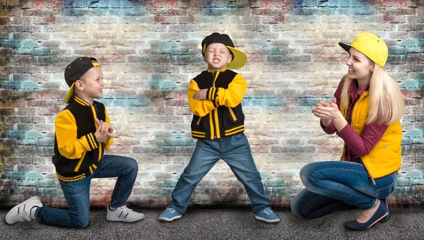 Une jeune mère et deux jeunes fils dans le style de l'espoir de hanche. Famille à la mode.Graffitis sur les murs . — Photo