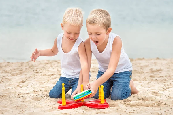 Two brothers are walking and playing on the beach.The game is a ring toss. — Stock Photo, Image