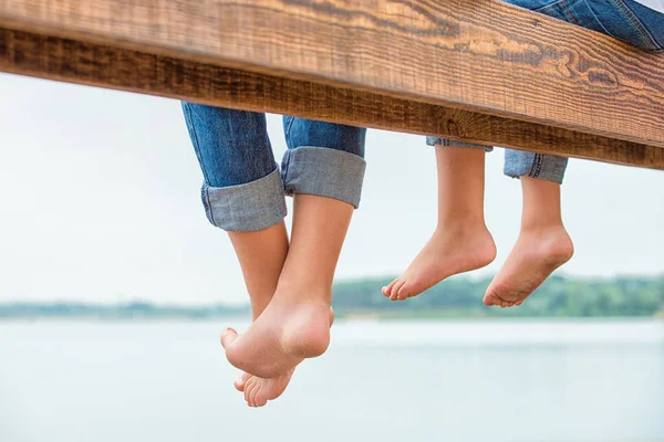 İki kardeş kendi ayakları ahşap iskele üzerinden salladı. Gölde aile tatil.