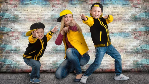 Une jeune mère et deux jeunes fils dans le style de l'espoir de hanche. Famille à la mode.Graffitis sur les murs . — Photo