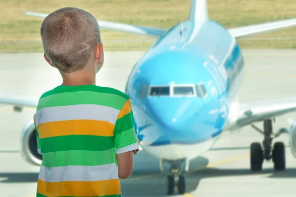 Das Kind blickt durch das Fenster des Flughafens auf das Flugzeug. — Stockfoto