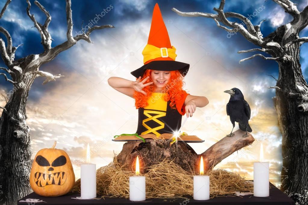 Halloween.The little witch,the child reads the spell in the sorcerer book.